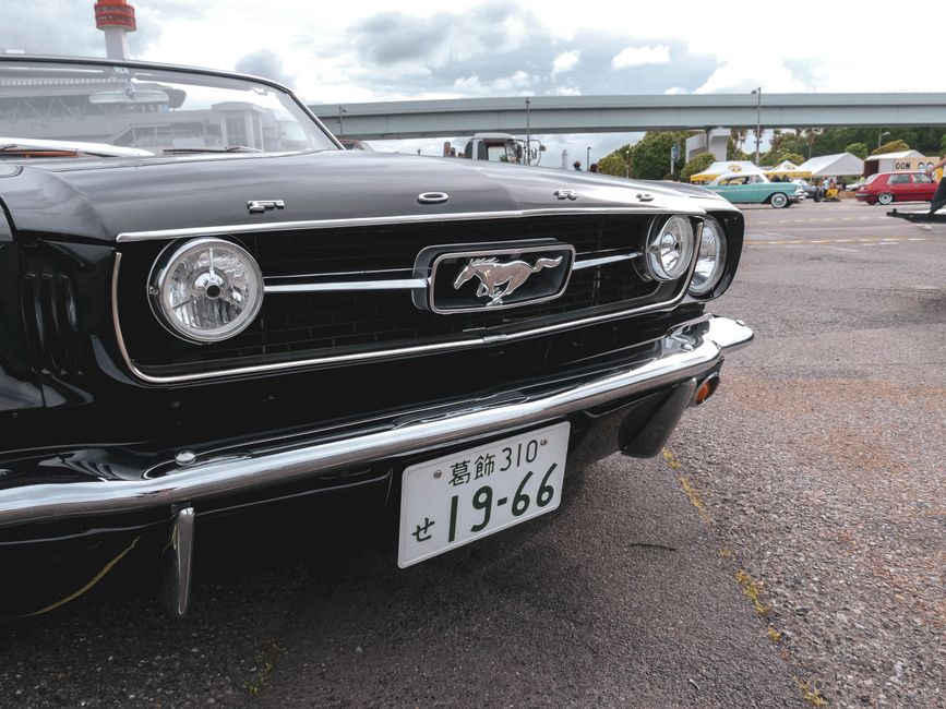 Close-up of a vintage black Ford Mustang displayed at an outdoor car meetup.