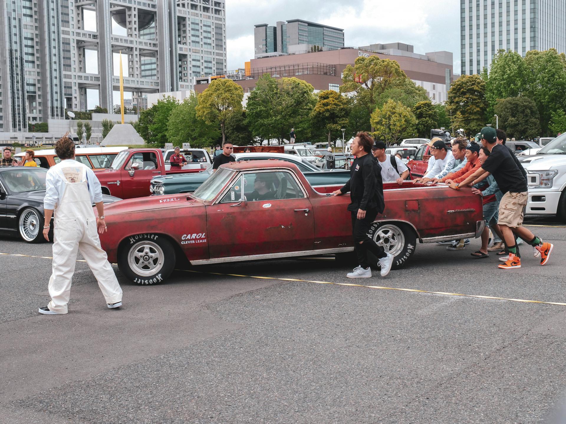 A group of people standing around an old car