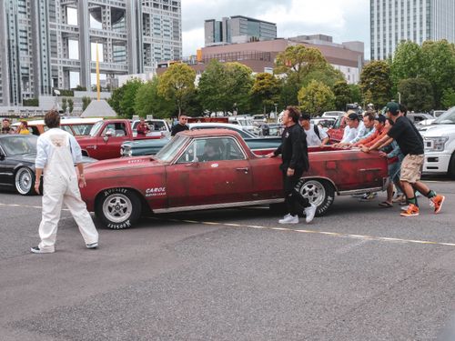 Free Group of people pushing a vintage muscle car at a city car gathering. Stock Photo