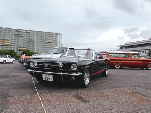 Free A classic black Ford Mustang at a vintage car meetup with an urban backdrop. Stock Photo