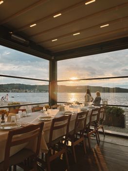 Elegant dining setting with sea view in Çanakkale, Türkiye during sunset; cozy ambiance.
