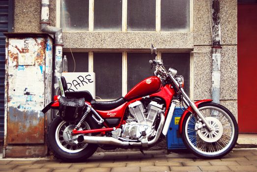 A classic red motorcycle parked against a textured urban wall in Varna, Bulgaria.