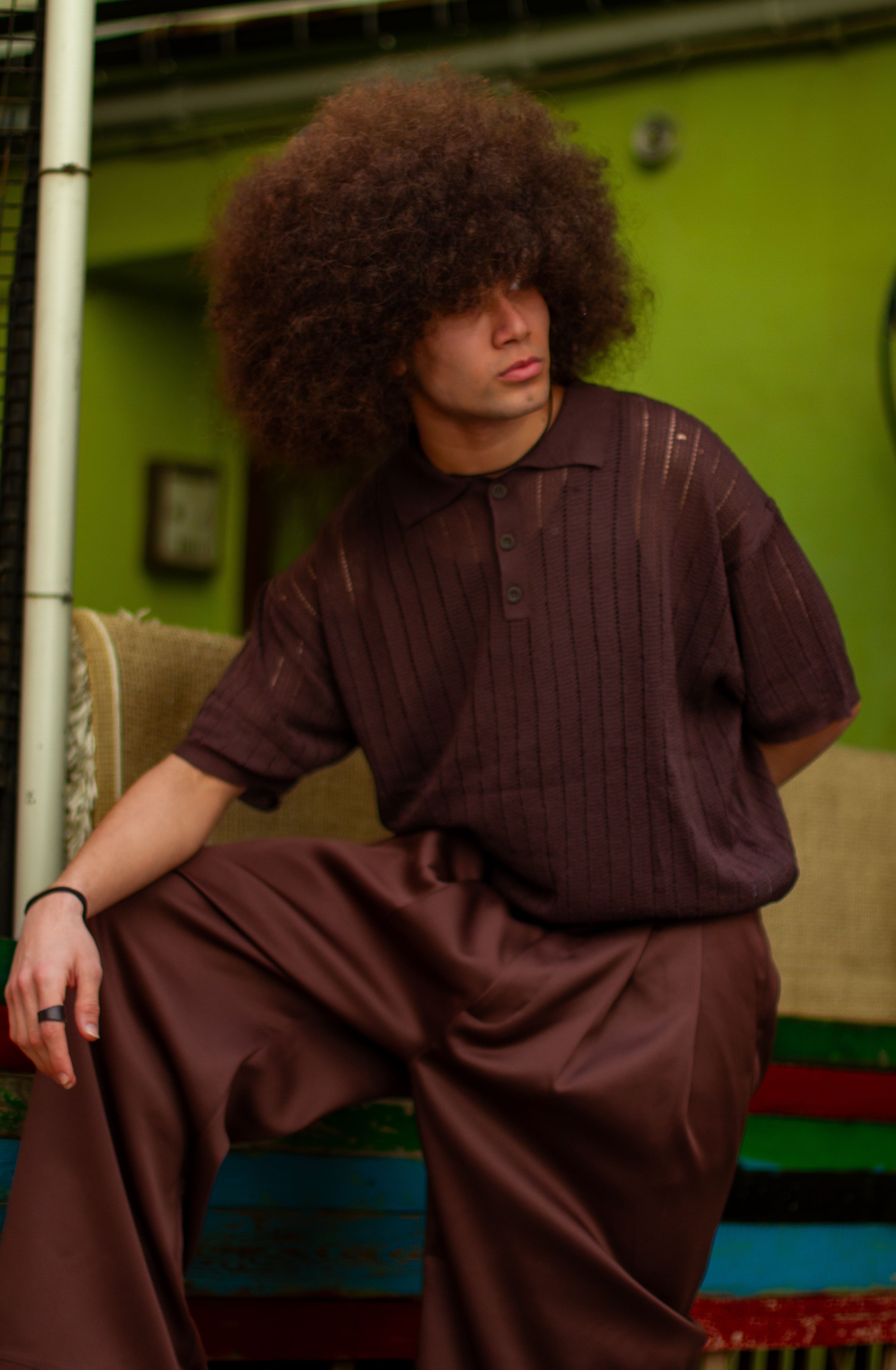 Captivating portrait of a man with afro hairstyle posing indoors in stylish retro attire.