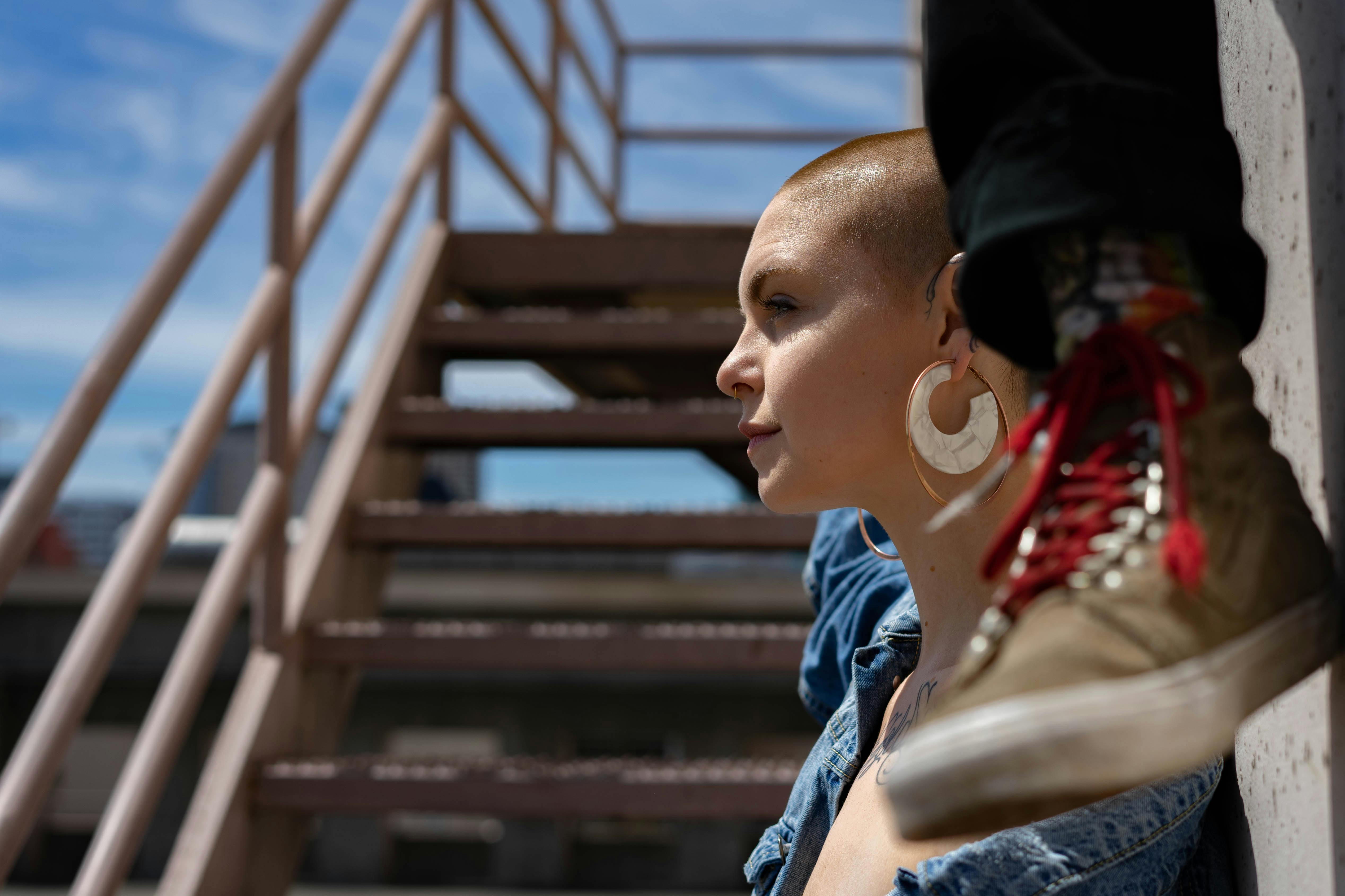 Stylish portrait of a young adult in denim on a staircase outdoors.