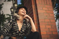 一位时尚女性在户外砖墙前开怀大笑，尽显时尚与欢乐