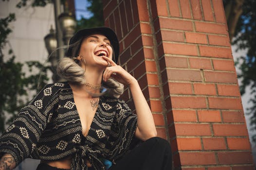 一位时尚女性在户外砖墙前开怀大笑，尽显时尚与欢乐