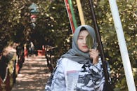 一位时尚女子戴着头巾站在户外，手拿一片叶子，拥抱大自然