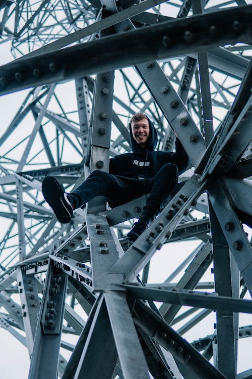 Low Angle Photography of Man Sitting on Metal Frames