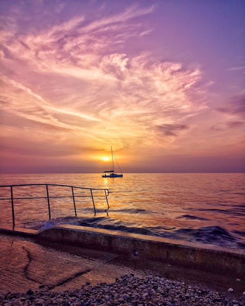 бесплатная Лодка, плывущая по океану во время заката Стоковое фото