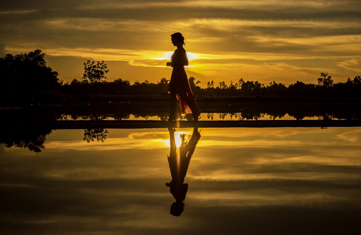 免费 男子站在湖上在日落时的剪影 素材图片