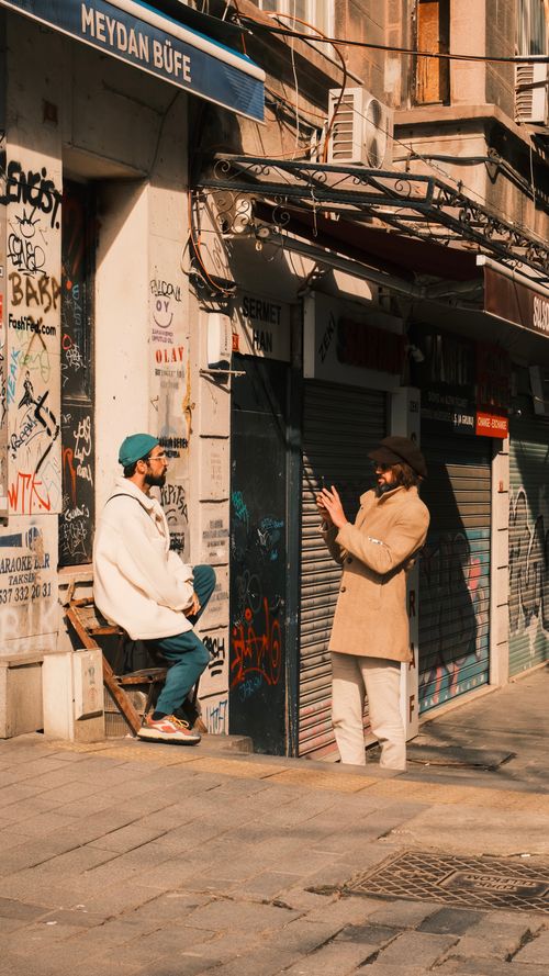 Free Two men in urban outfits engaged in street photography near a graffiti-covered store. Stock Photo
