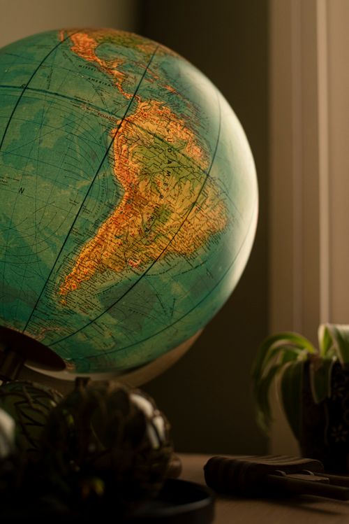 Free Close-up view of a vintage world globe on a table, with warm lighting and a cozy atmosphere. Stock Photo