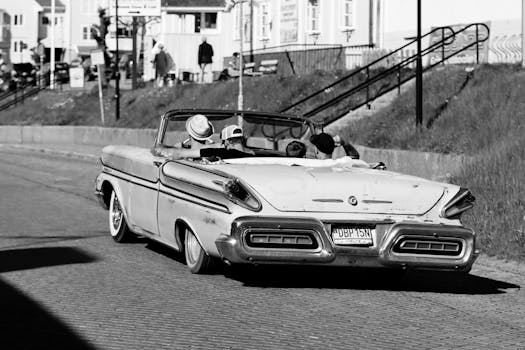 Black and white photo of a vintage convertible cruising through Jönköping, Sweden, capturing nostalgic street life.