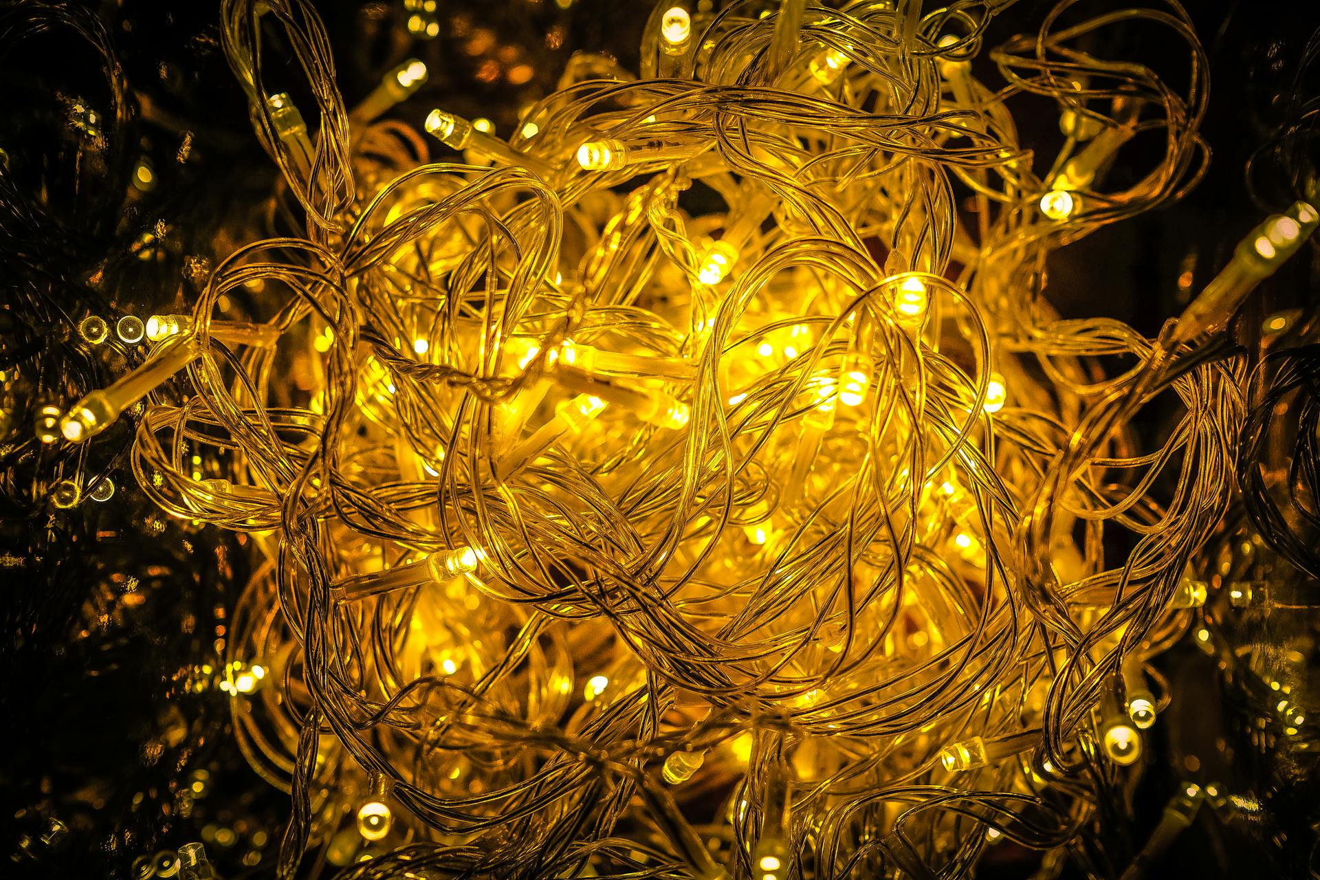 Close-up of tangled golden string lights illuminating with festive glow, perfect for holiday decor.