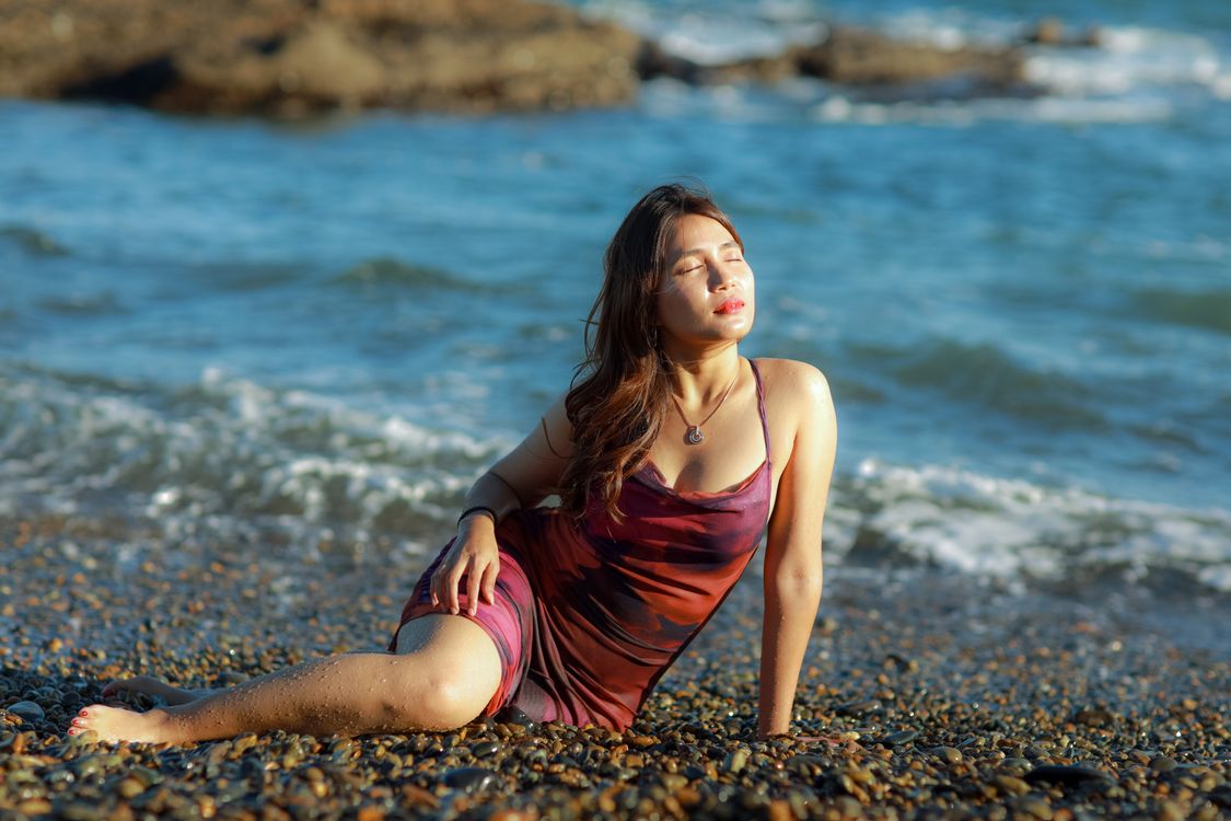 Woman in a Red Dress Sitting on a Beach with her Eyes Closed · Free ...