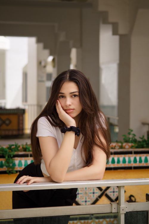 Free Portrait of a brunette woman leaning on a railing, exuding a contemplative mood. Stock Photo
