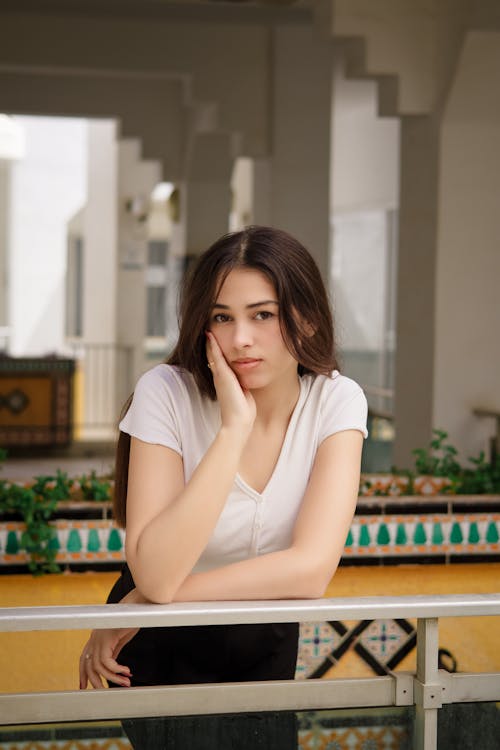 A woman leaning on a railing with her hand on her chin