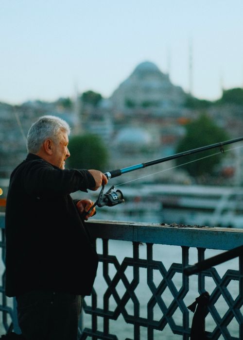 Free Elderly man fishing on Galata Bridge with cityscape background in Istanbul. Stock Photo