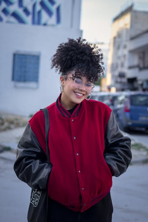 A young woman with curly hair and glasses smiles