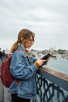 A woman operates a drone from Galata Bridge with a cityscape in the background.