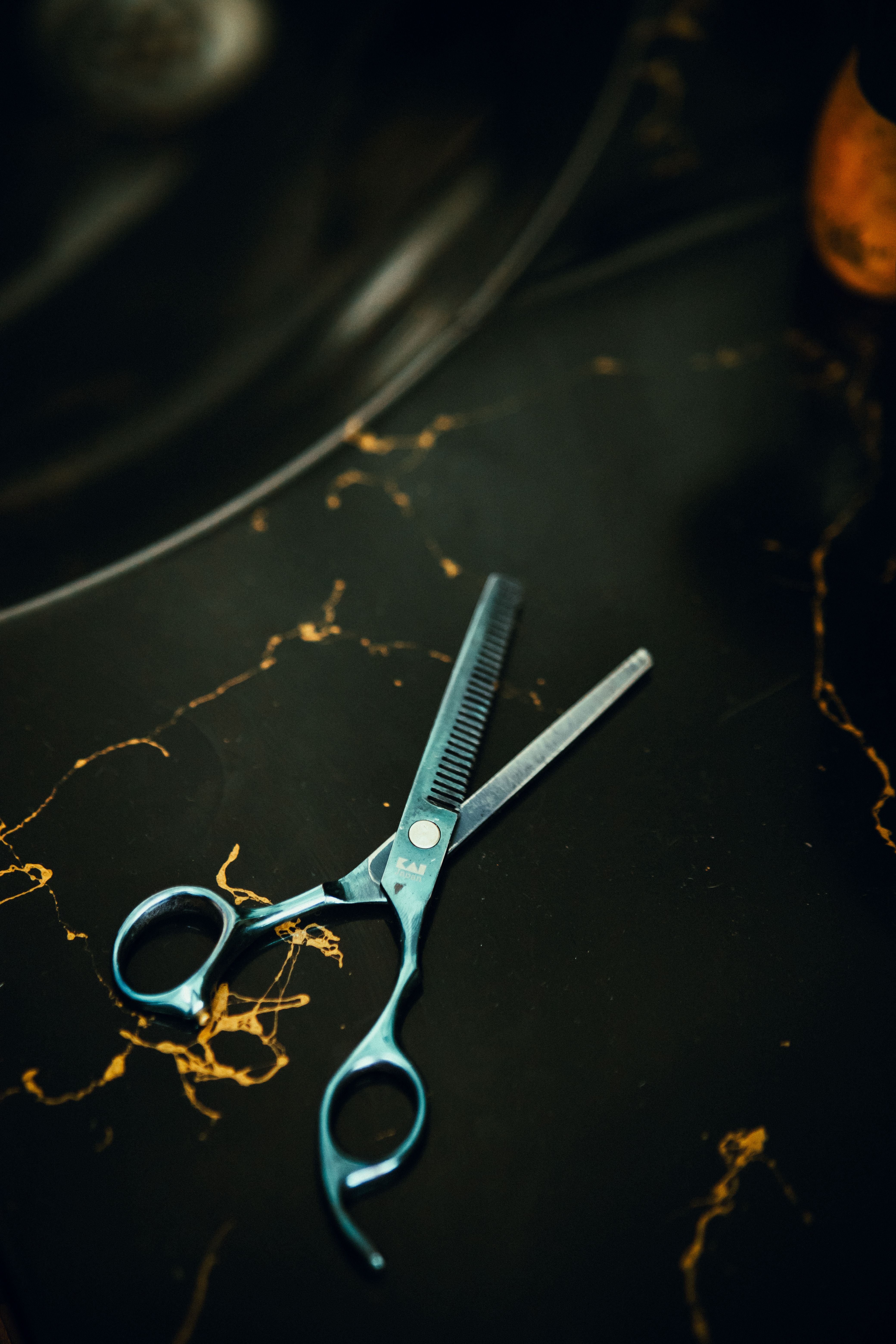 Close-up of professional hair thinning shears on a dark marble surface, perfect for hair styling and salon themes.
