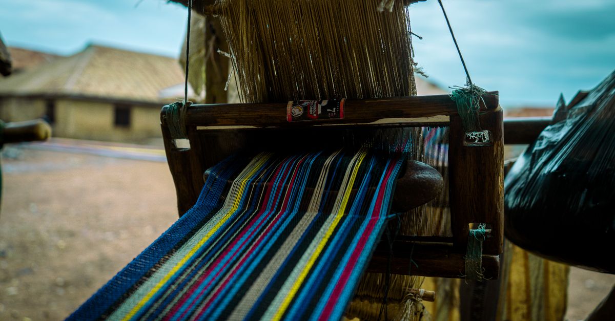 Women weaving Kente cloth on traditional looms in a village