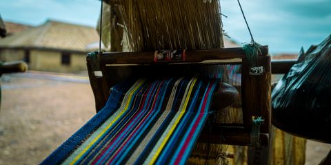 Close-up of a traditional handloom weaving a colorful textile in a rural setting.