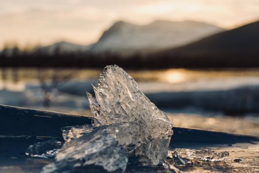 Glistening ice crystals by a frozen lake under a warm sunset.
