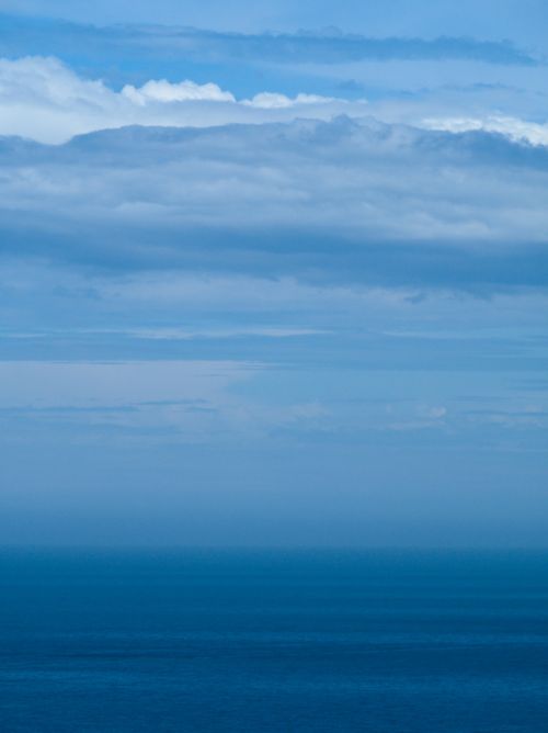 Free A tranquil ocean scene showcasing an endless horizon beneath a vivid blue sky filled with clouds. Stock Photo