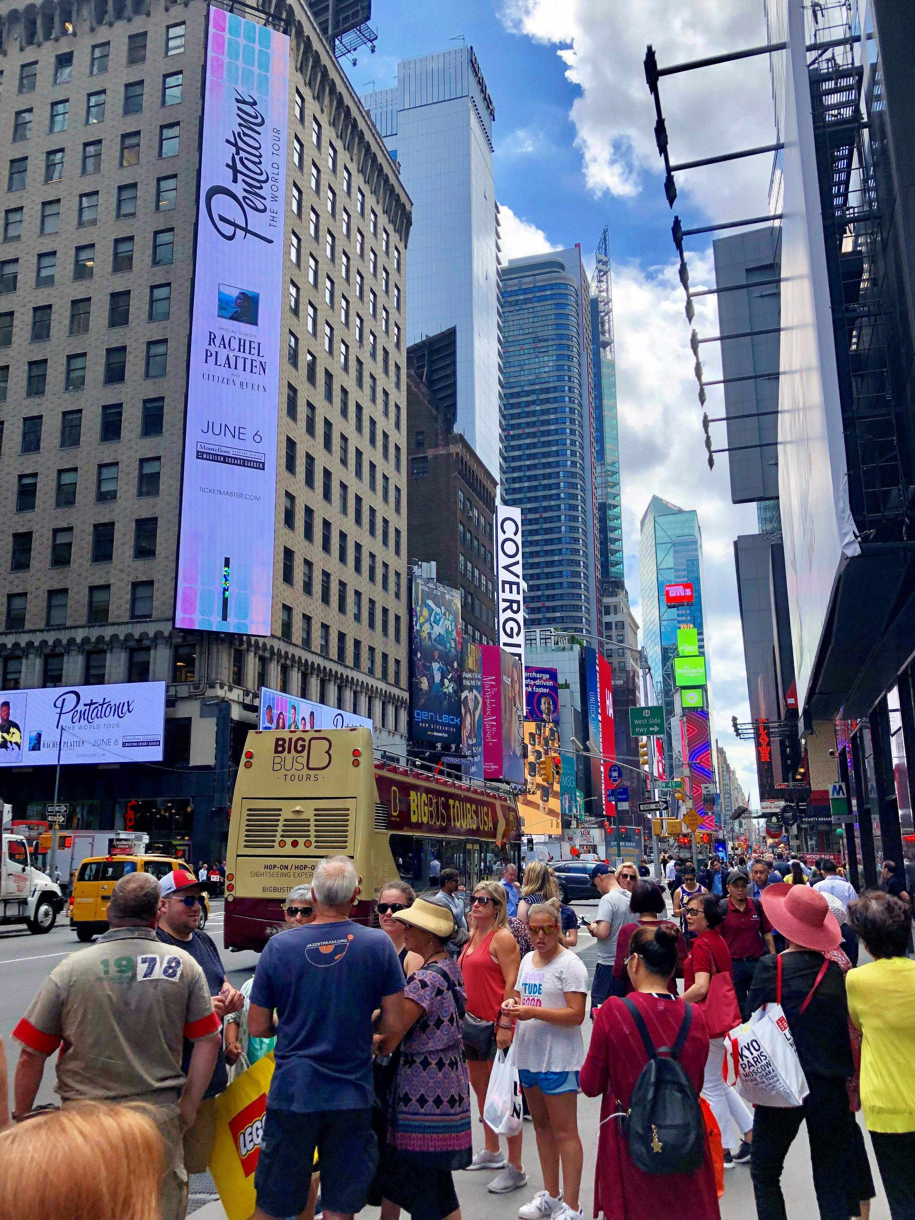 时代广场繁忙的一天里，明亮的天空下，热闹的人群和标志性的摩天大楼被捕捉下来