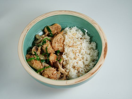 Teal bowl with sauteed chicken, shimeji mushrooms and garlic chives beside sesame-sprinkled white rice