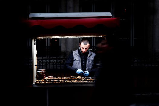 A street vendor in Istanbul sells roasted chestnuts under a warm light in an urban setting at night.