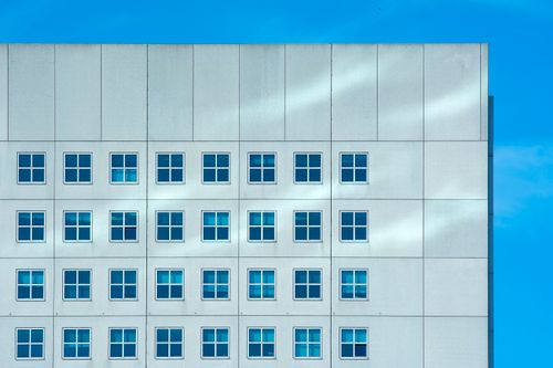 Free Modern building facade with windows against clear blue sky in Rotterdam. Stock Photo