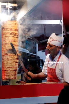 A street vendor skillfully slices doner kebab at a food stall in Istanbul, Türkiye.