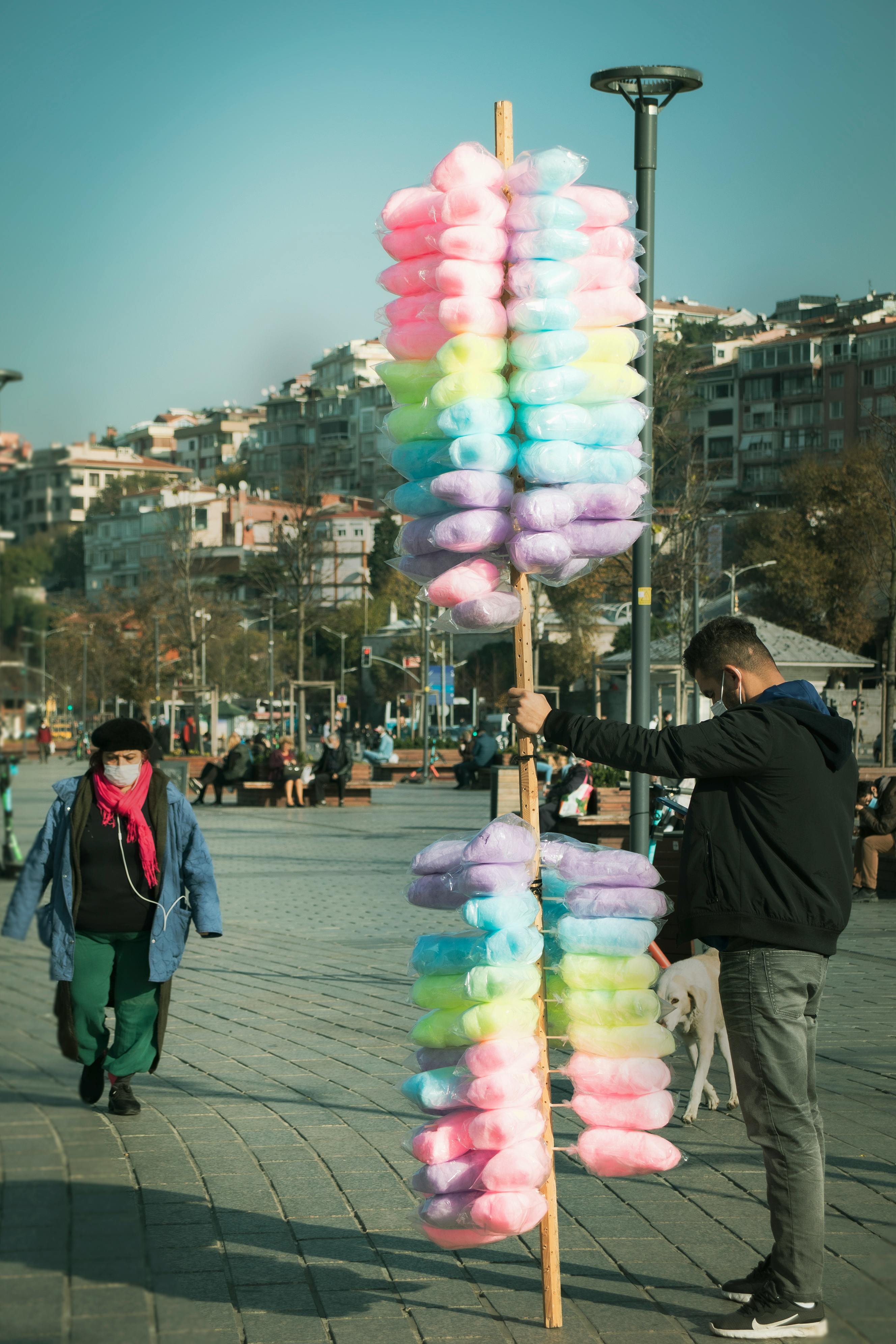 Man selling vibrant candyfloss in a busy street of İstanbul, capturing the lively urban atmosphere.