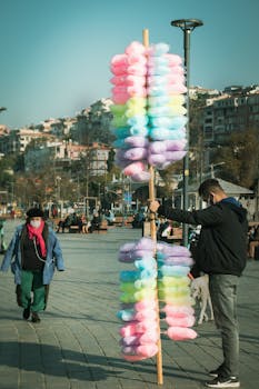 Man selling vibrant candyfloss in a busy street of İstanbul, capturing the lively urban atmosphere.