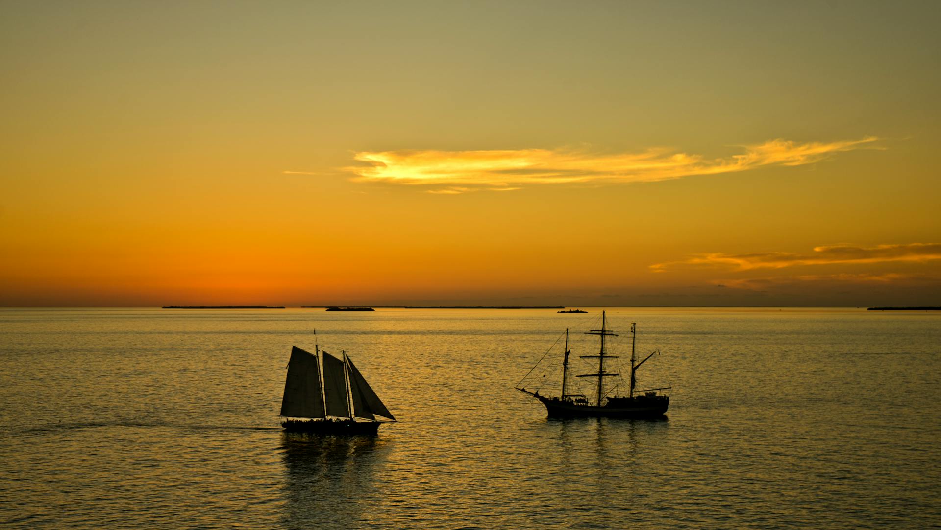 Stunning silhouette of sailing ships against a warm Key West sunset skyline.
