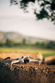 Drone resting on a rustic stone with blurred green landscape in the background.