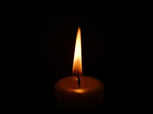 A candle is lit in the dark with a black background