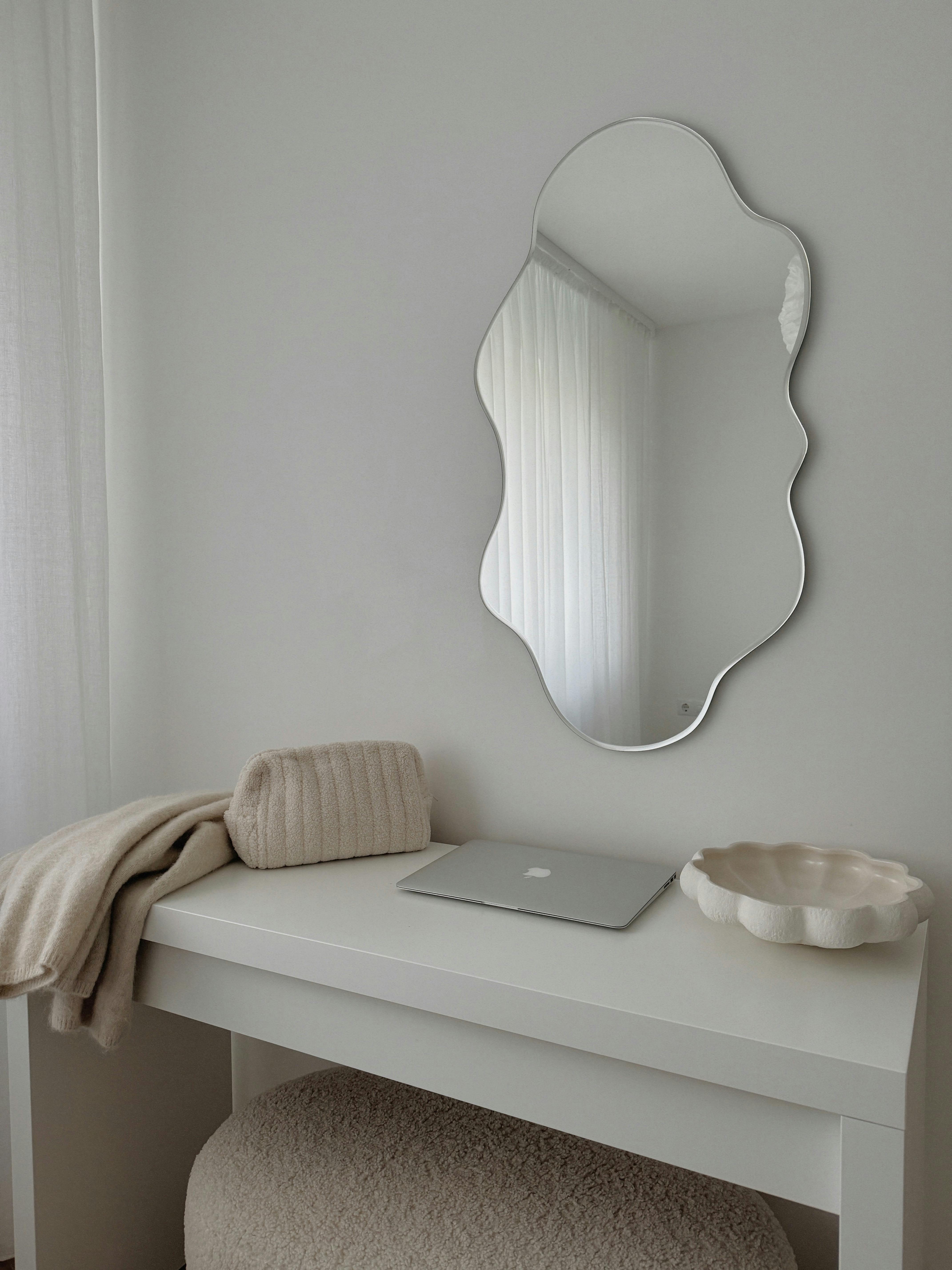 Elegant minimalist vanity featuring a decorative mirror, laptop, and cozy blankets.