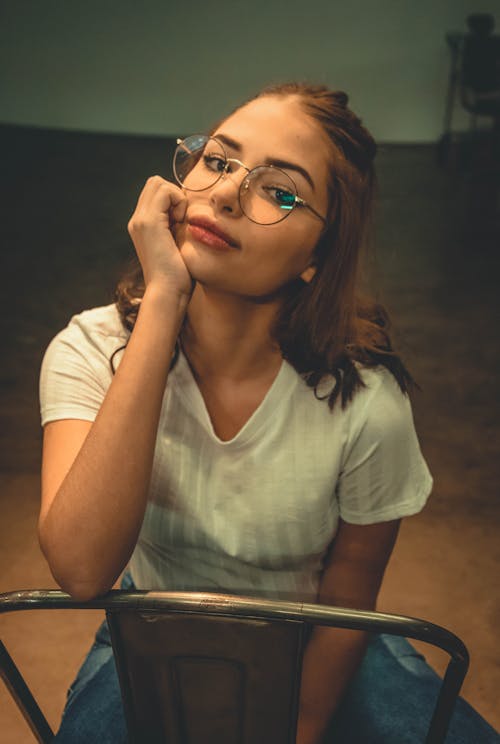 Free Photo of a woman wearing eyeglasses sitting on a chair Stock Photo