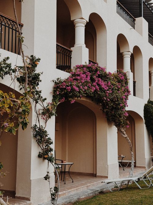 Free Elegant Mediterranean-style building facade with vibrant bougainvillea and classic arches. Stock Photo