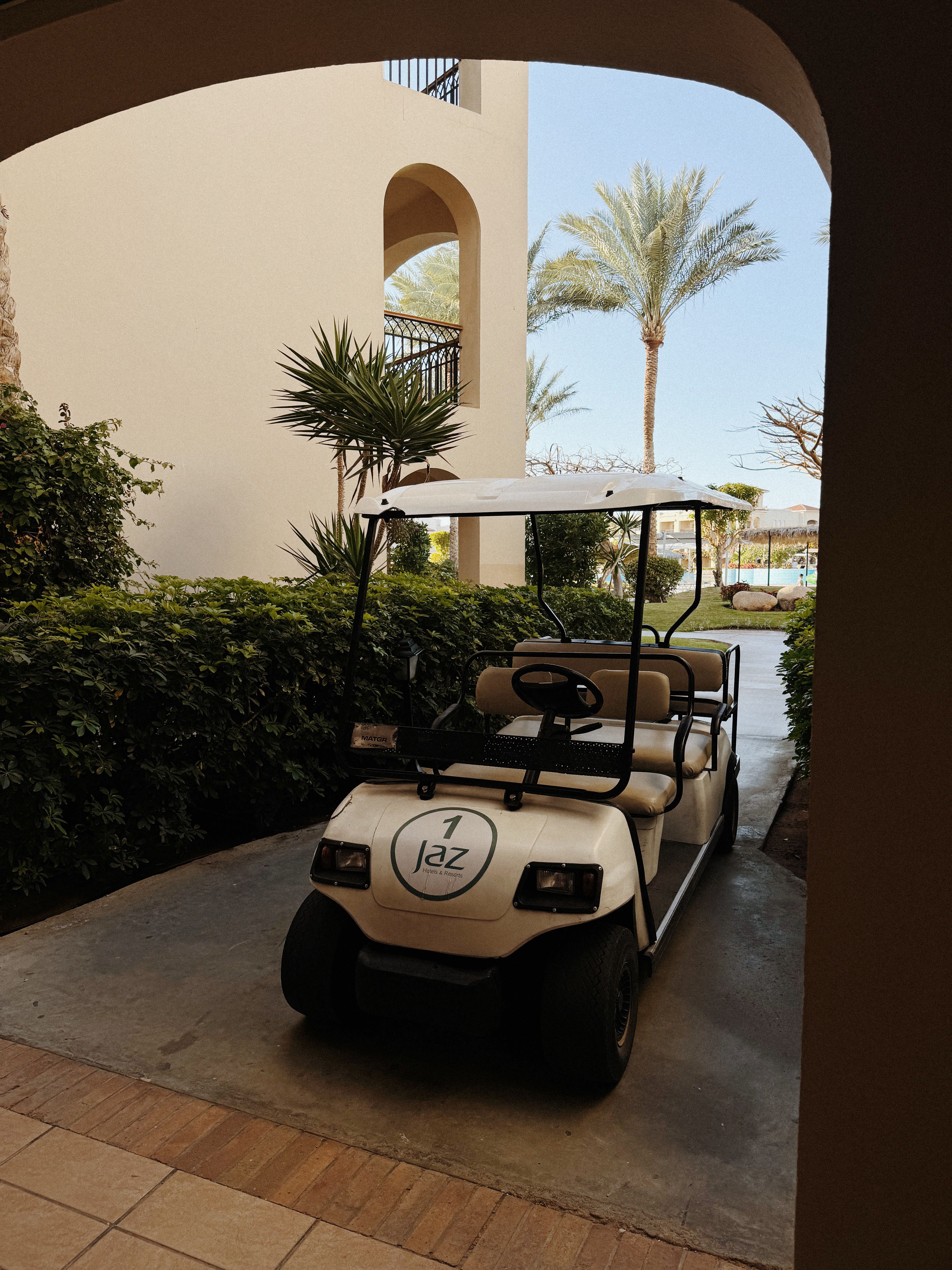 A golf cart parked at the entrance of a luxurious resort, surrounded by lush greenery.