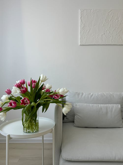A white couch with a vase of tulips on it