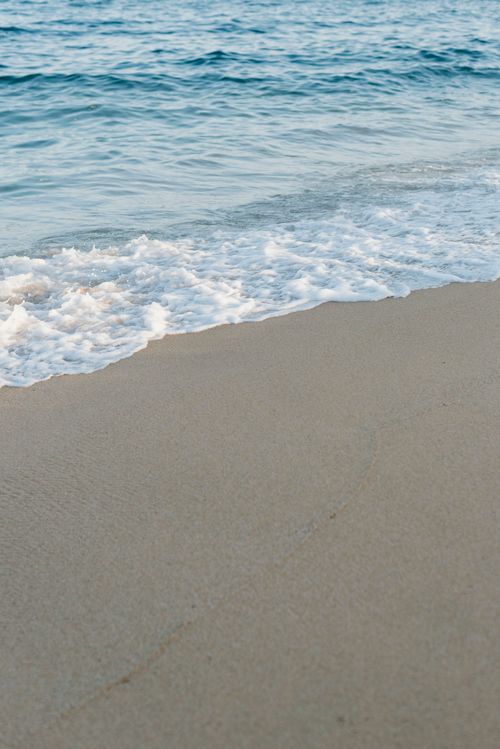 Free Gentle sea waves lapping against a sandy beach under a clear sky, perfect for relaxation. Stock Photo