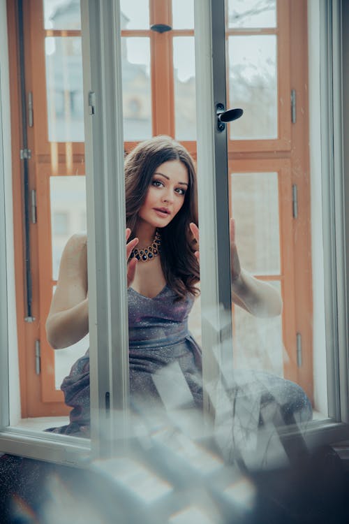 A woman in a dress looking out of a window