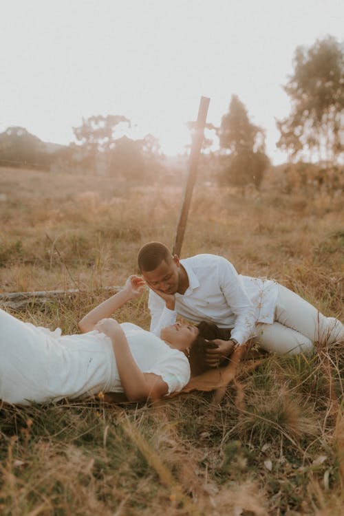 Free Couple Lying Down on Grassland at Sunset Stock Photo