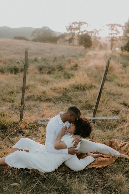 A couple is sitting on the ground in a field