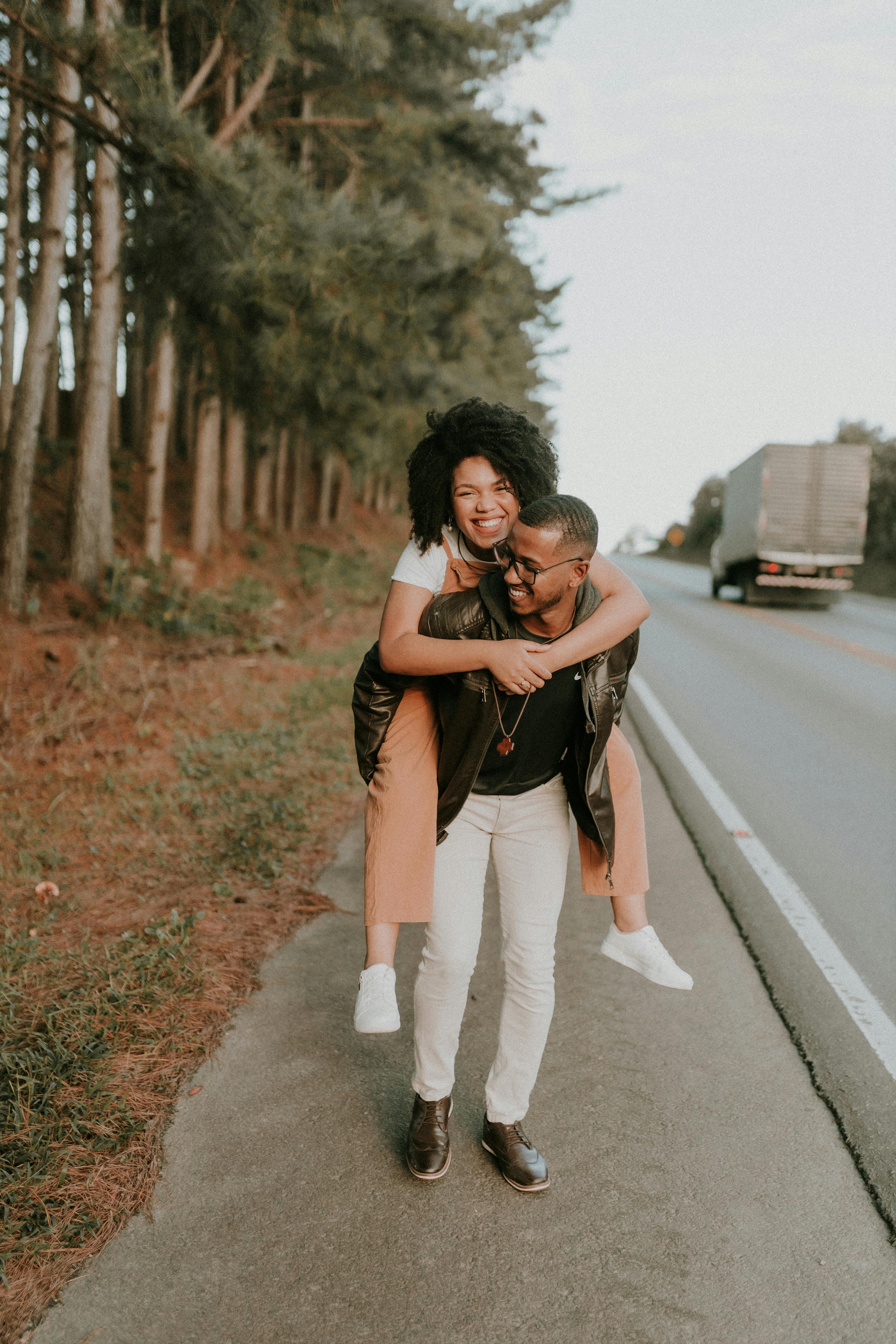 smiling man carrying woman on road