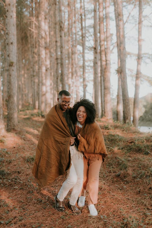 A couple in a forest wrapped in blankets